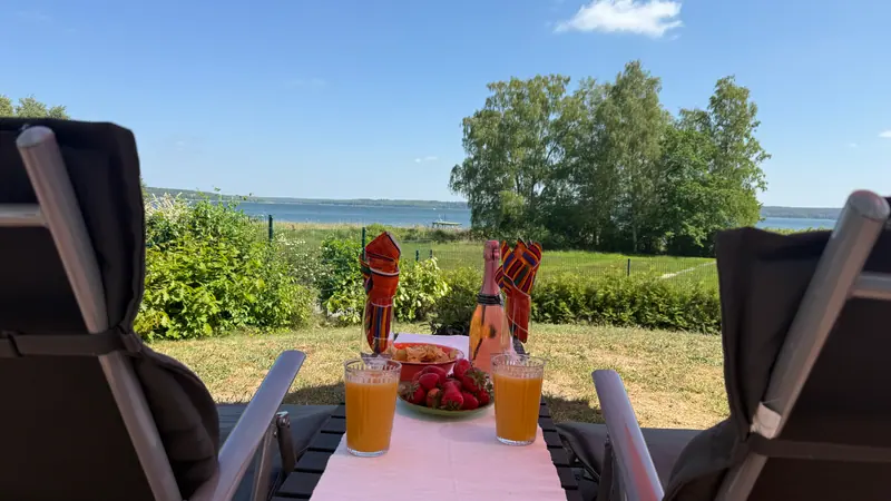 Gedeckter Tisch auf der Terrasse mit Blick über die Wiese auf den Plauer See