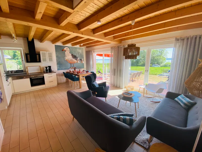 Wohnbereich mit zwei Sofas, Sesseln und Blick in die offene Küche